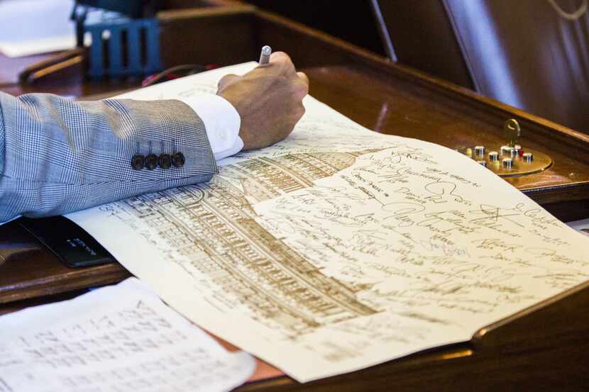 Rep. Eddie Lucio III, D-Brownsville adds his signature to a drawing of the capitol during...
