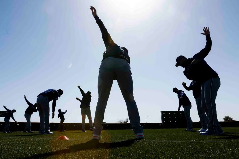Texas Rangers players stretch on the field during spring training workout at the team's...