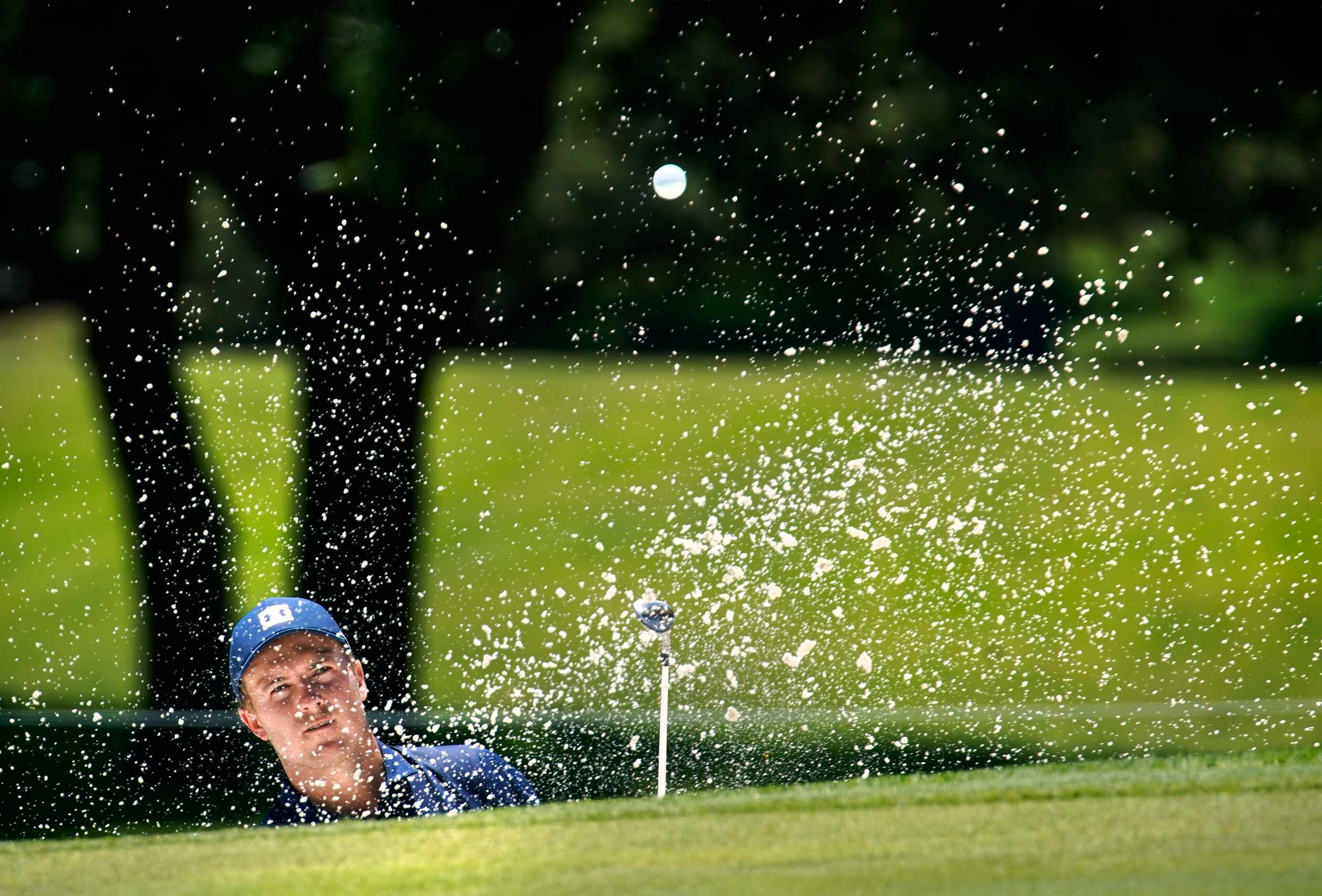 PGA Tour golfer Jordan Spieth splashes his ball out of the greenside bunker on No. 2 during...
