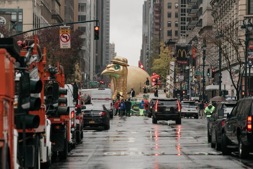 A large float makes its way along the parade route behind police barricades.