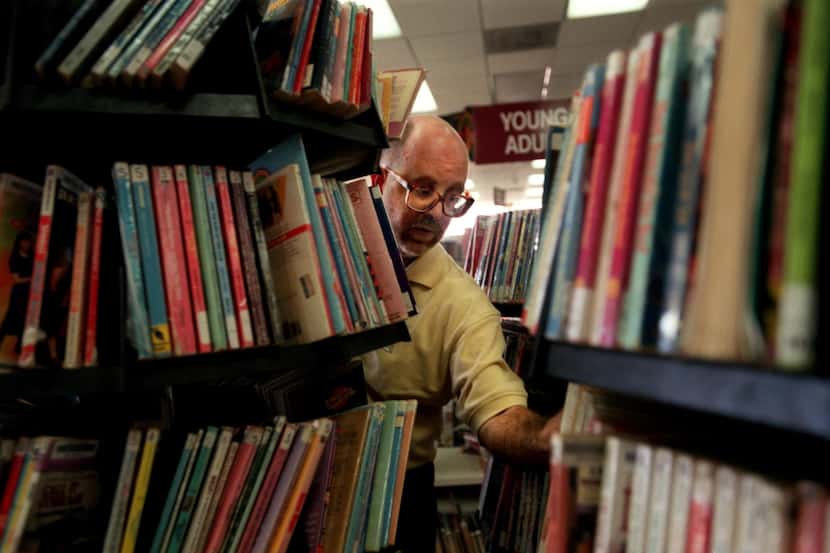 Charles David Smith, 39, puts away books at the North Oak Cliff Branch Library where he...