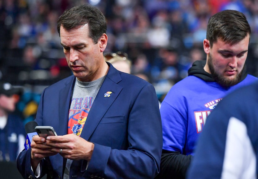 Rob Riggle checks his phone in the second half as the University Kansas takes on Villanova...