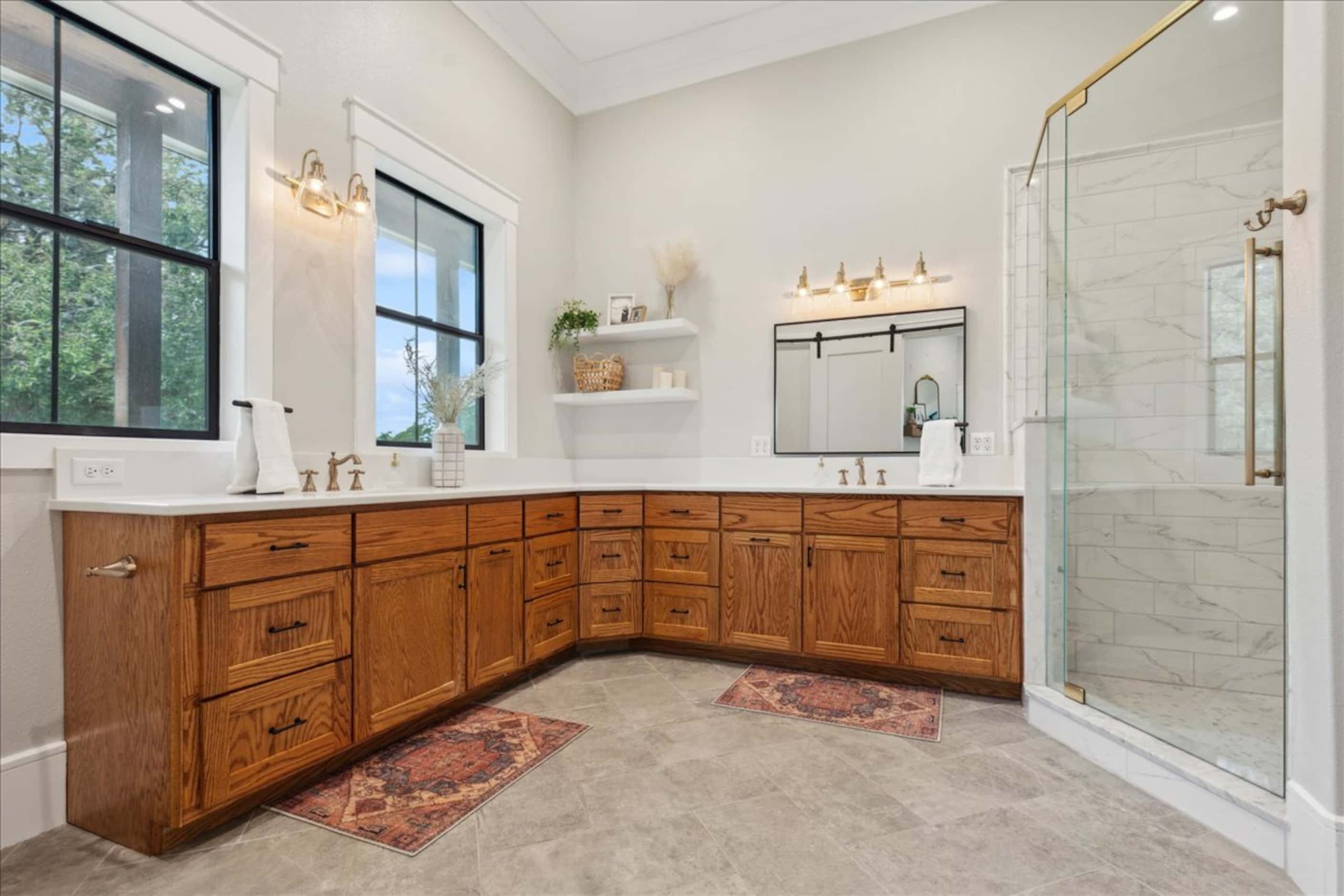 Bathroom with wood cabinets, neutral tile and flooring and two sinks
