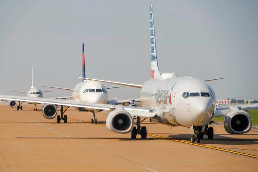 American Airlines and Delta Air Lines jets line up for takeoff at DFW International Airport.