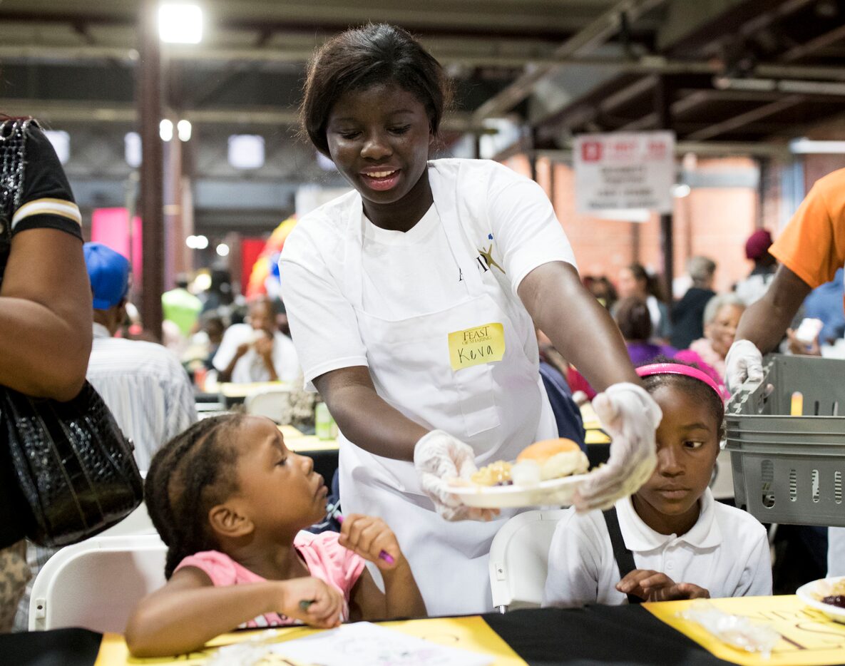 Volunteer Chakevia Smith (center) of Lancaster High School serves a plate of Thanksgiving...