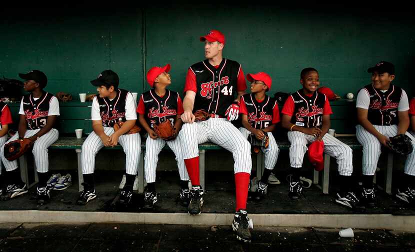 Dallas Mavericks center Shawn Bradley relaxes in the dugout with a group of young baseball...