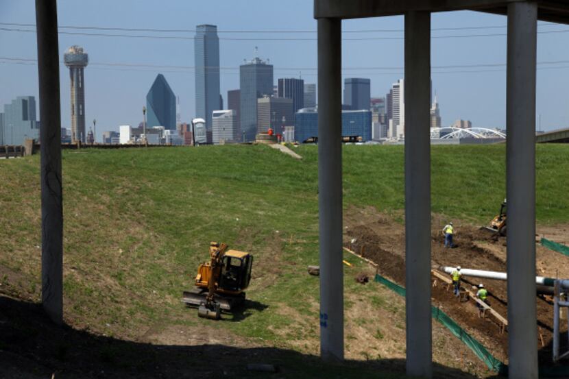 A construction crew worked on the west Trinity River levee under the Jefferson Boulevard...