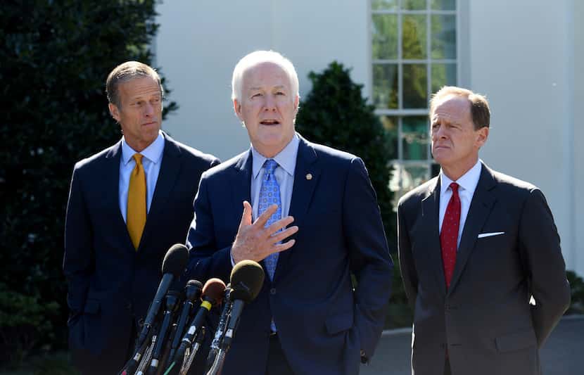 Sen. John Cornyn, then the majority whip, speaks to the media at the White House, flanked by...