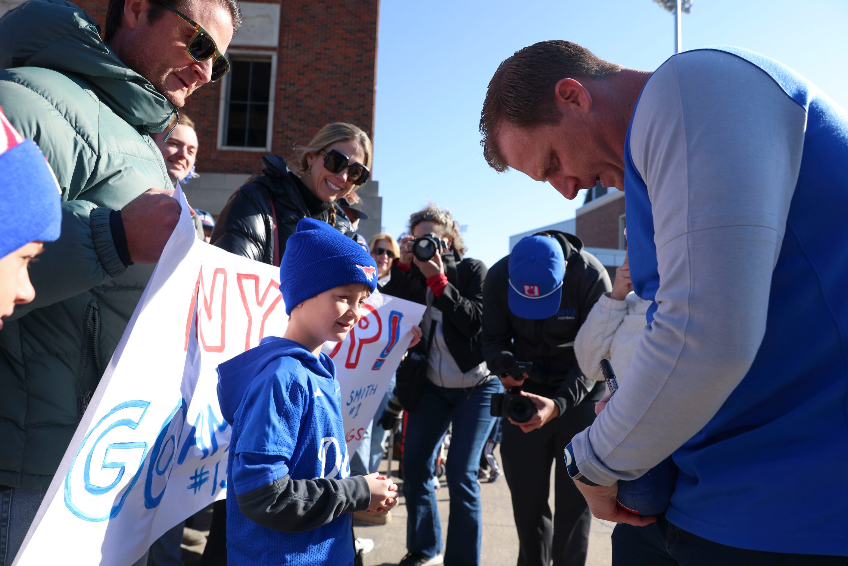 Will Mayon, 8, receives an autograph from SMU head coach Rhett Lashlee during a send-off...