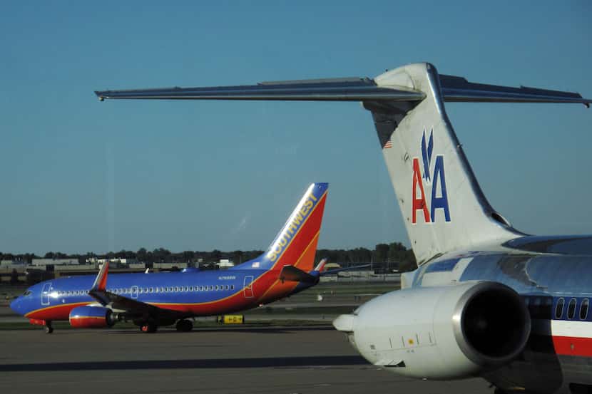  A Southwest Airlines jet taxis past a Dallas-bound American Airlines jet parked at a gate...