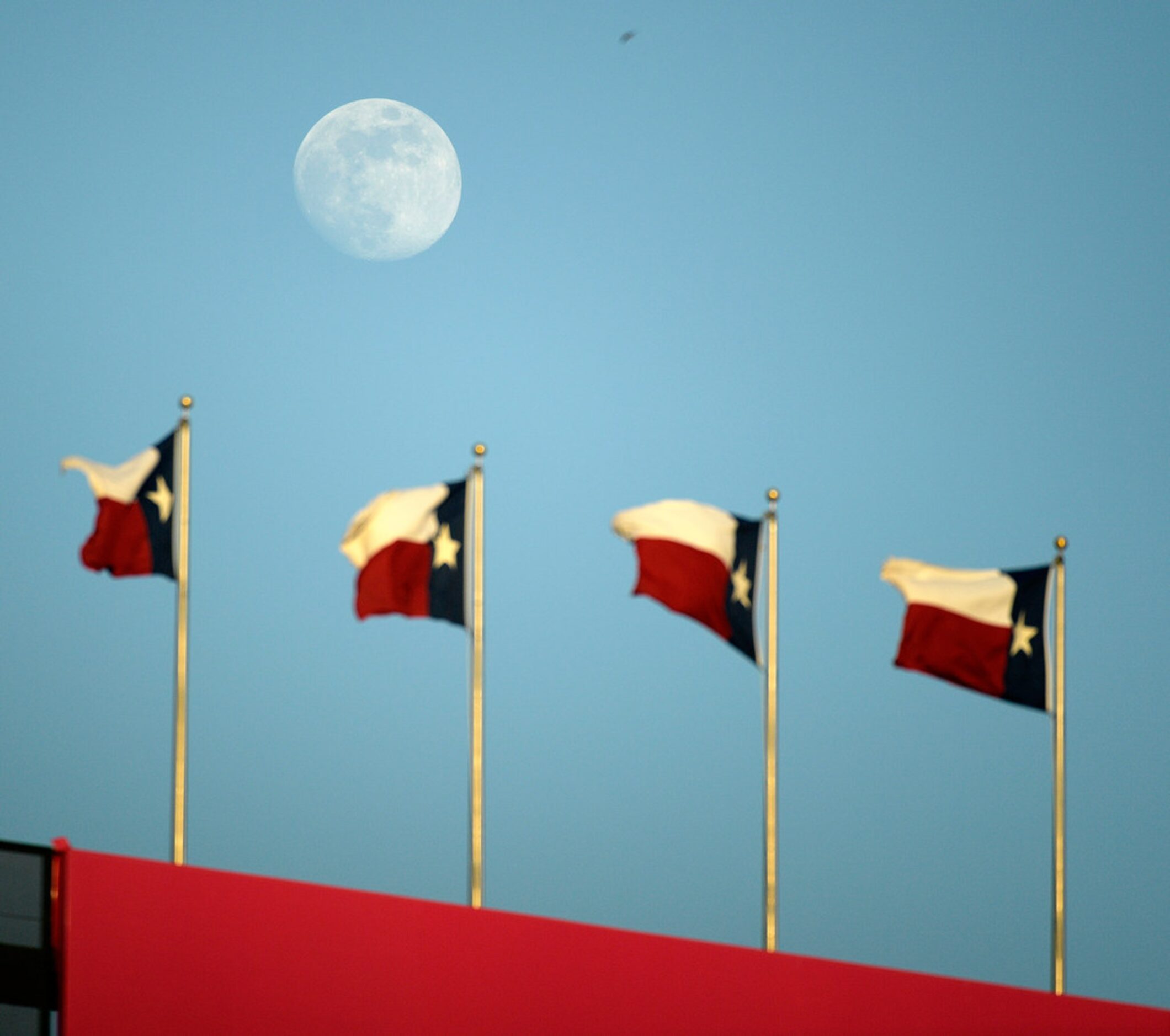 The moon over the center field Texas Flags during the third inning as the Rangers play the...