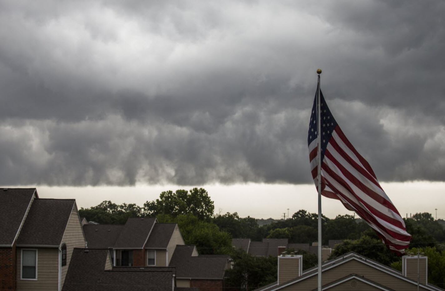 A storm moves over an American flag at Lakewood Greens apartments on Friday in Dallas....