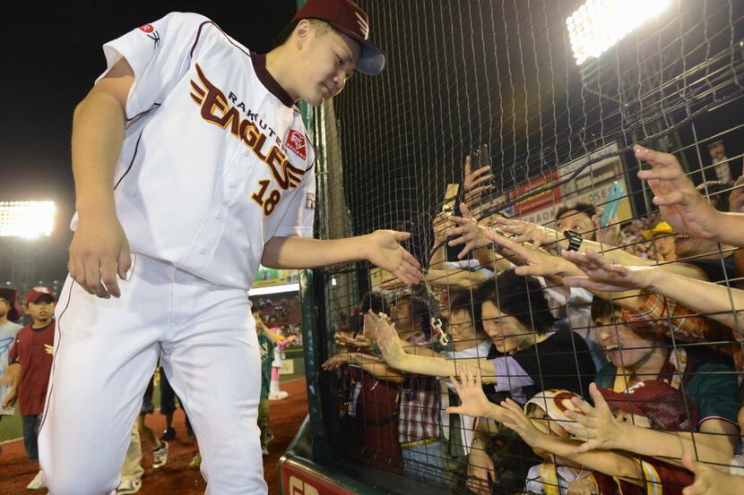 Rakuten Eagles pitcher Masahiro Tanaka is given high five by his fans after pitching against...