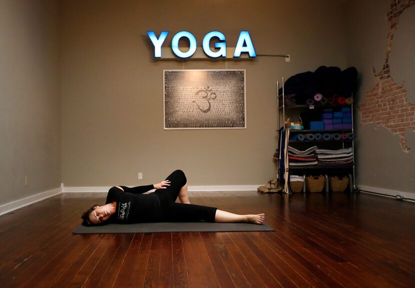 Brandie Sellers stretches before teaching a Sunday morning yoga class at Yoga Balance Studio...