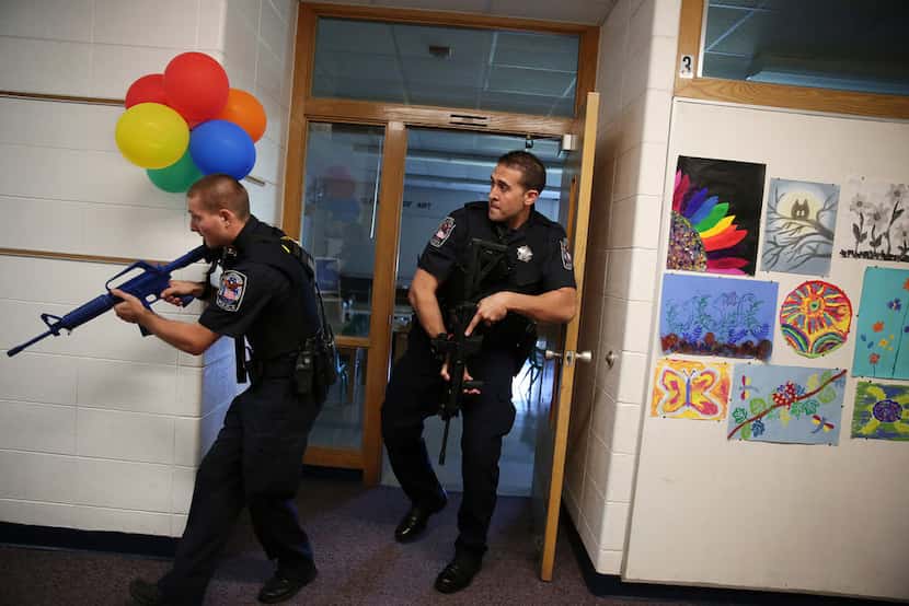 Two police officers carry blank weapons as they participate in an active shooter exercise...