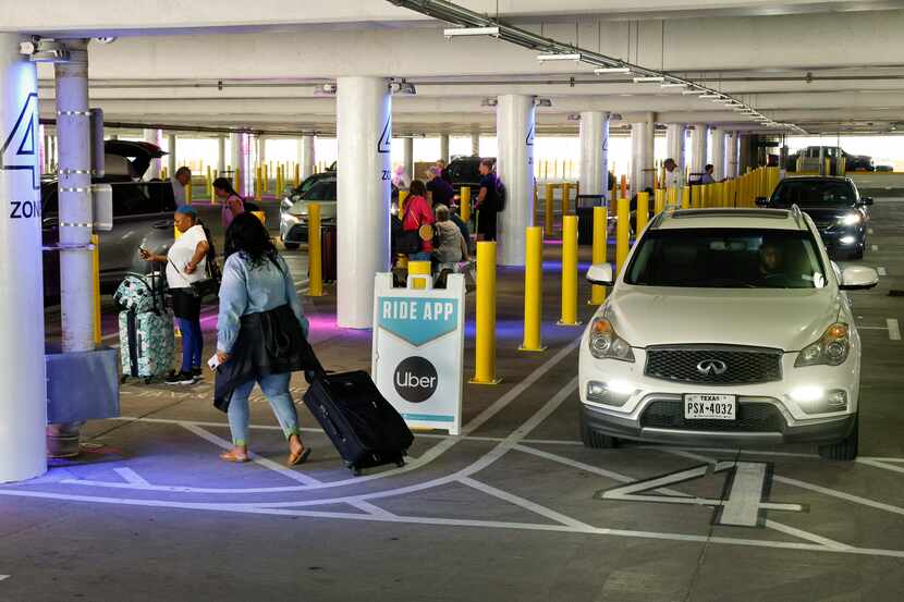 Travelers walk to meet their drivers in the new pickup location for Uber, Lyft and taxis in...