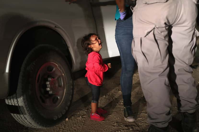 A 2-year-old Honduran asylum seeker cries as her mother is searched and detained near the...