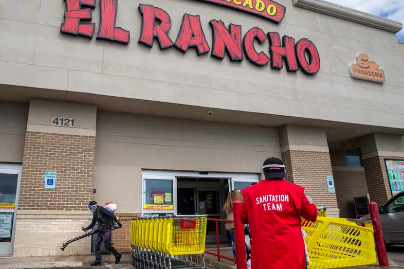 Jorge Osorio (izq) sanatiza las afueras del supermercado El Rancho en Gaston Avenue en...