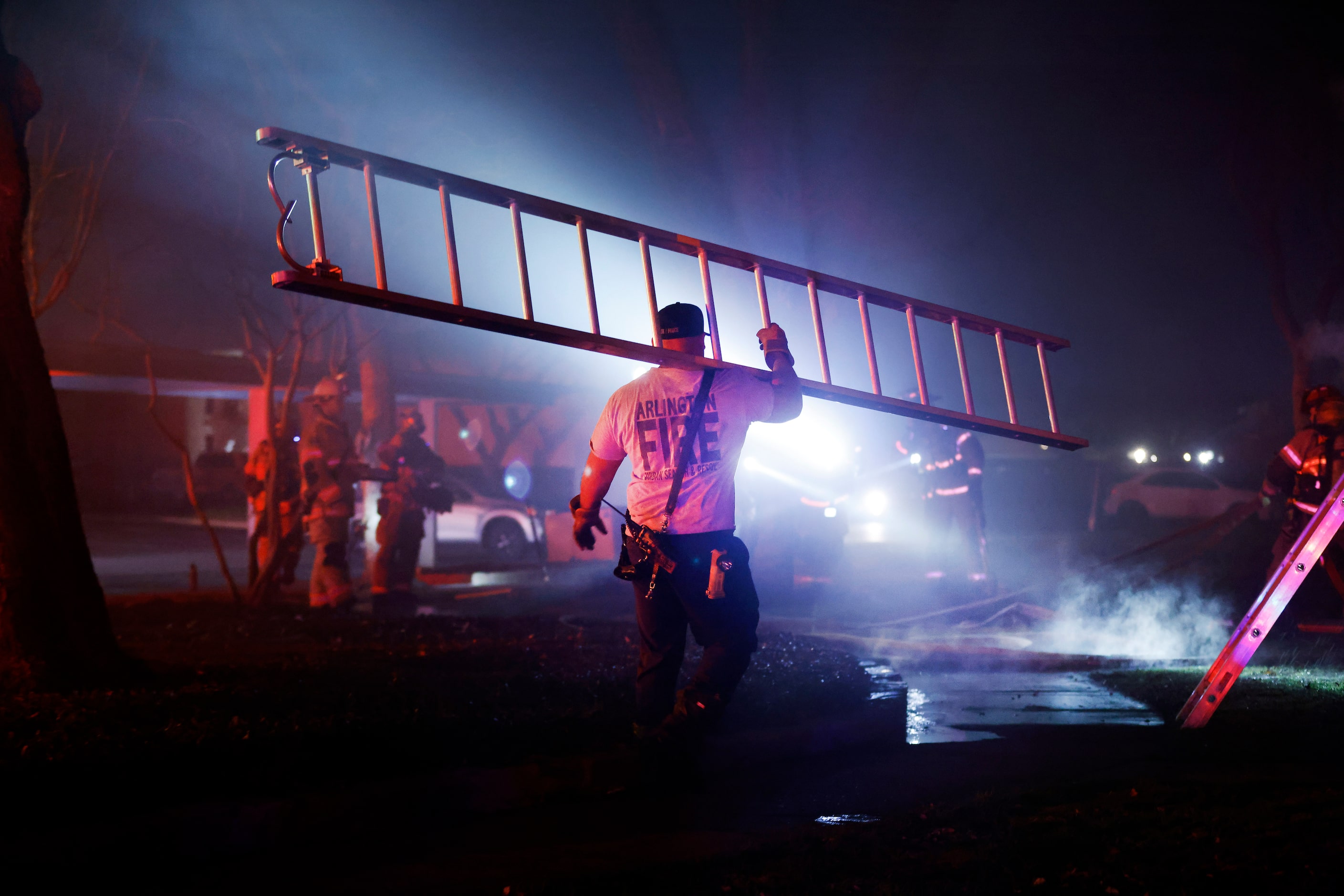 An Arlington firefighter carries a padder to the scene  of a two-alarm blaze at the Rise...