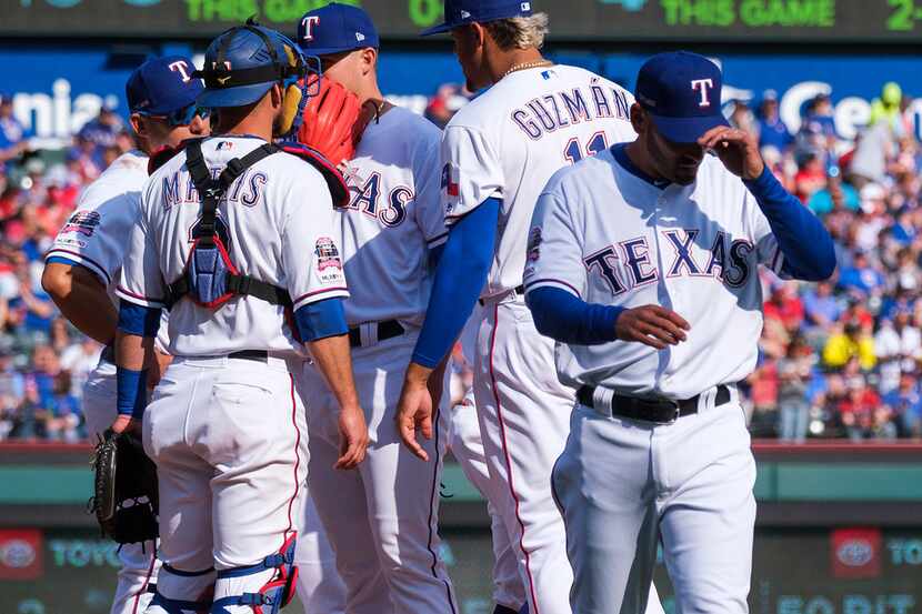 Texas Rangers manager Chris Woodward heads back to the dugout after replacing pitcher...