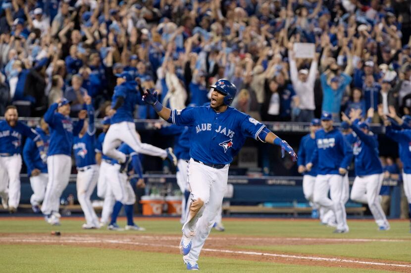Toronto Blue Jays' Edwin Encarnacion celebrates while he rounds the bases after hitting a...