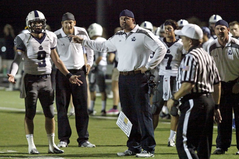 Liberty High School quarterback Foster Ford (9) and head coach Greg Price (center) quiz the...