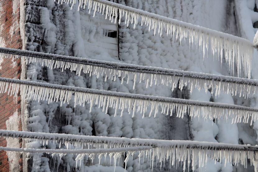 Icicles hang from utility and power lines near the scene of an overnight blaze in west...