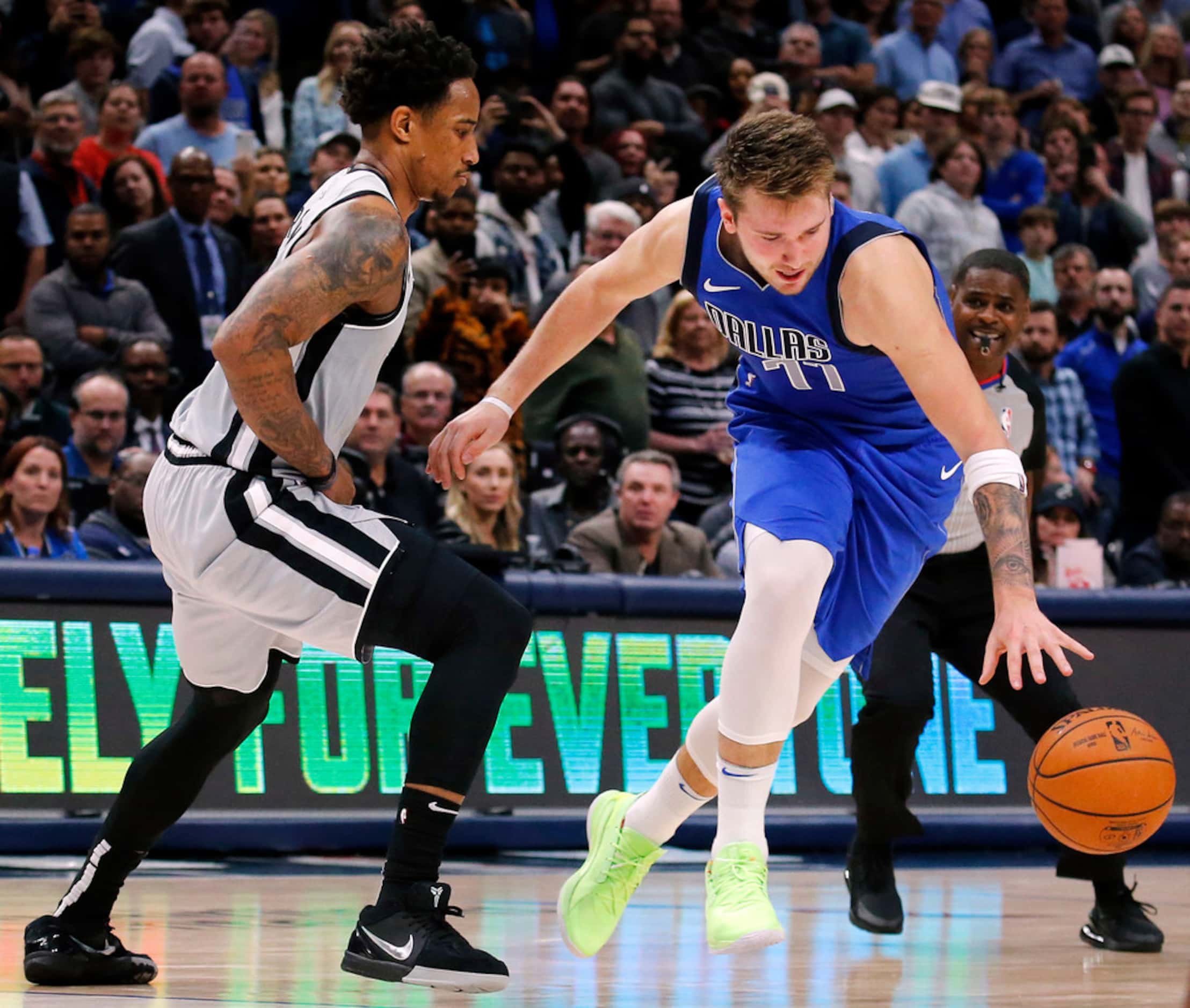 Dallas Mavericks forward Luka Doncic (77) tries to keep the dribble alive after running into...