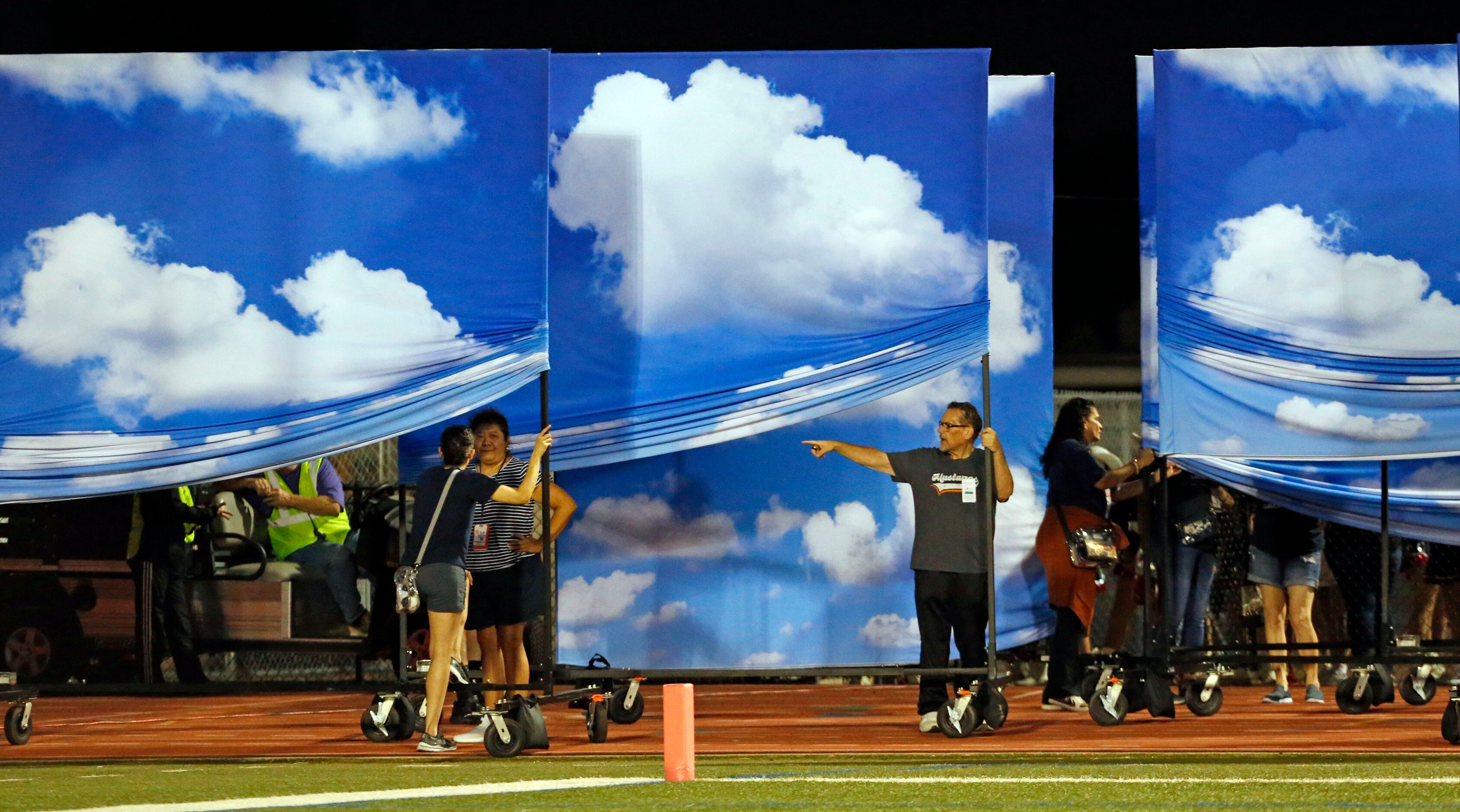 Sachse Band parents position cloud banners in preparation for the school’s halftime show...