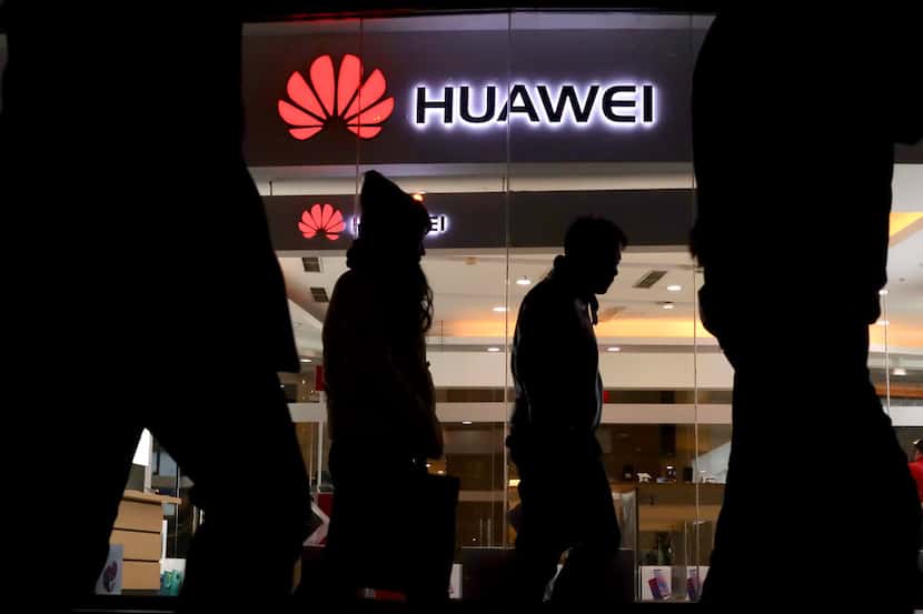 Pedestrians walk past a Huawei retail shop in Beijing Thursday, Dec. 6, 2018. China on...
