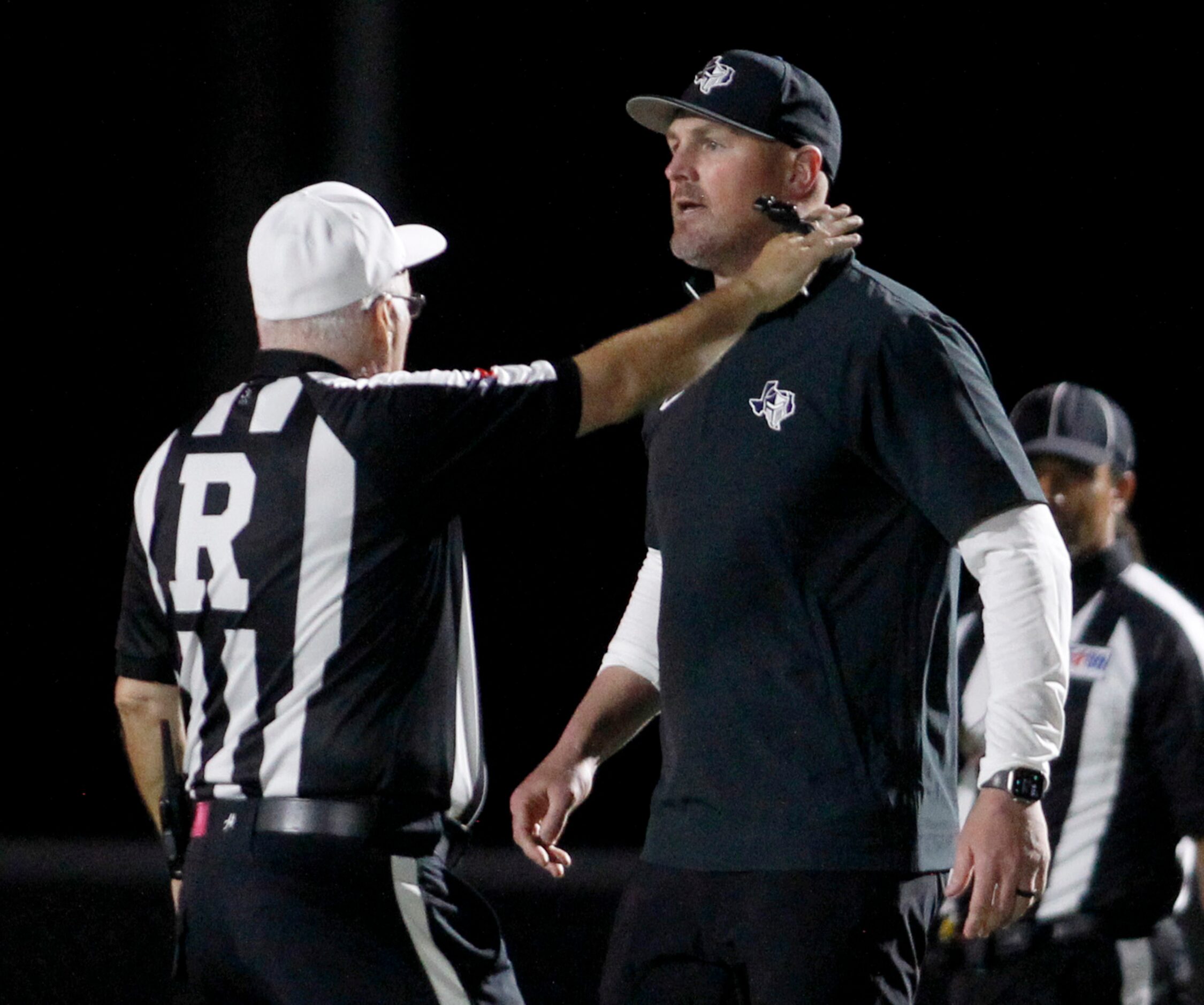 A game official works to control Argyle Liberty Christian head coach Jason Witten as he...