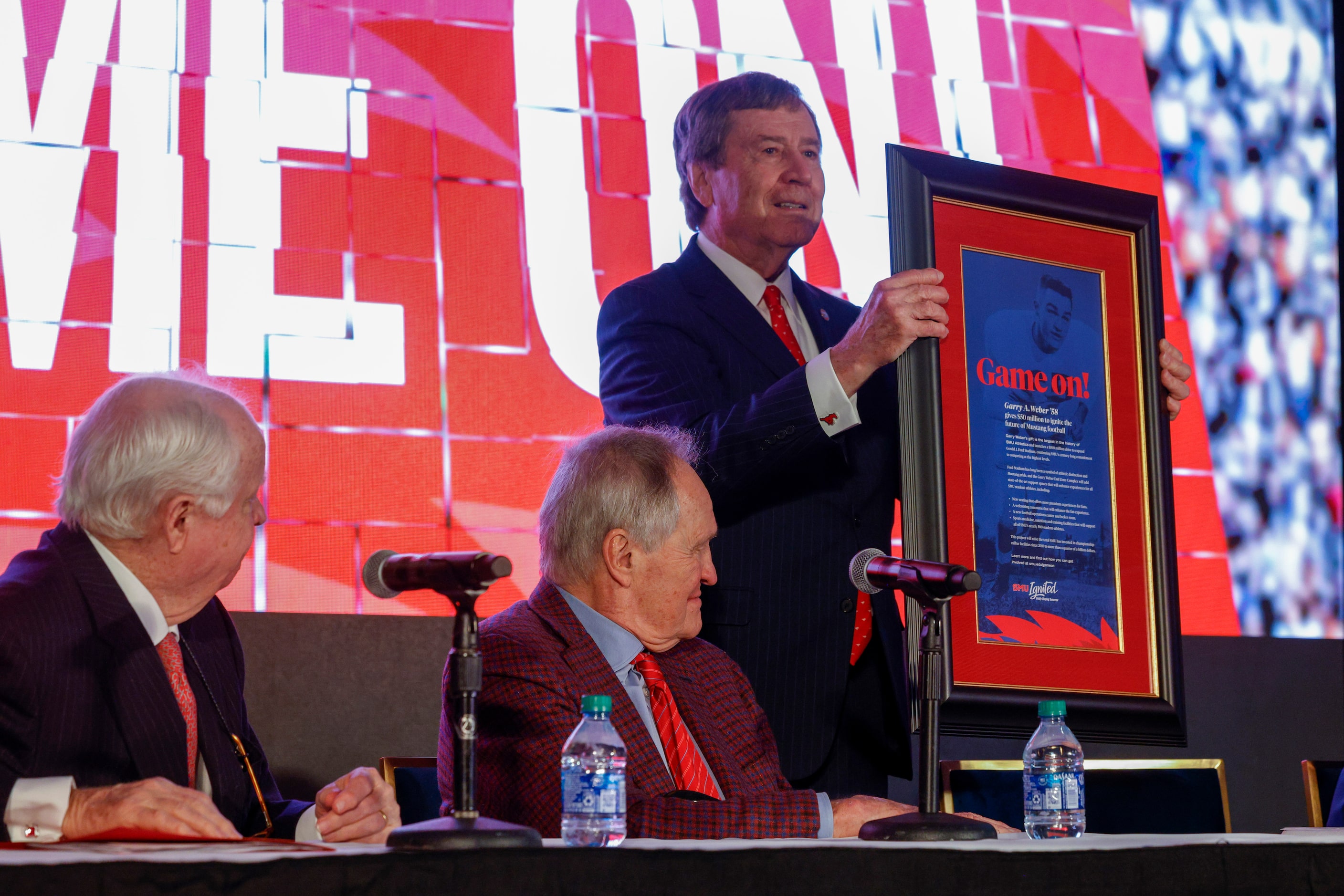 SMU President R. Gerald Turner presents SMU alumnus Garry Weber with a framed copy of a full...