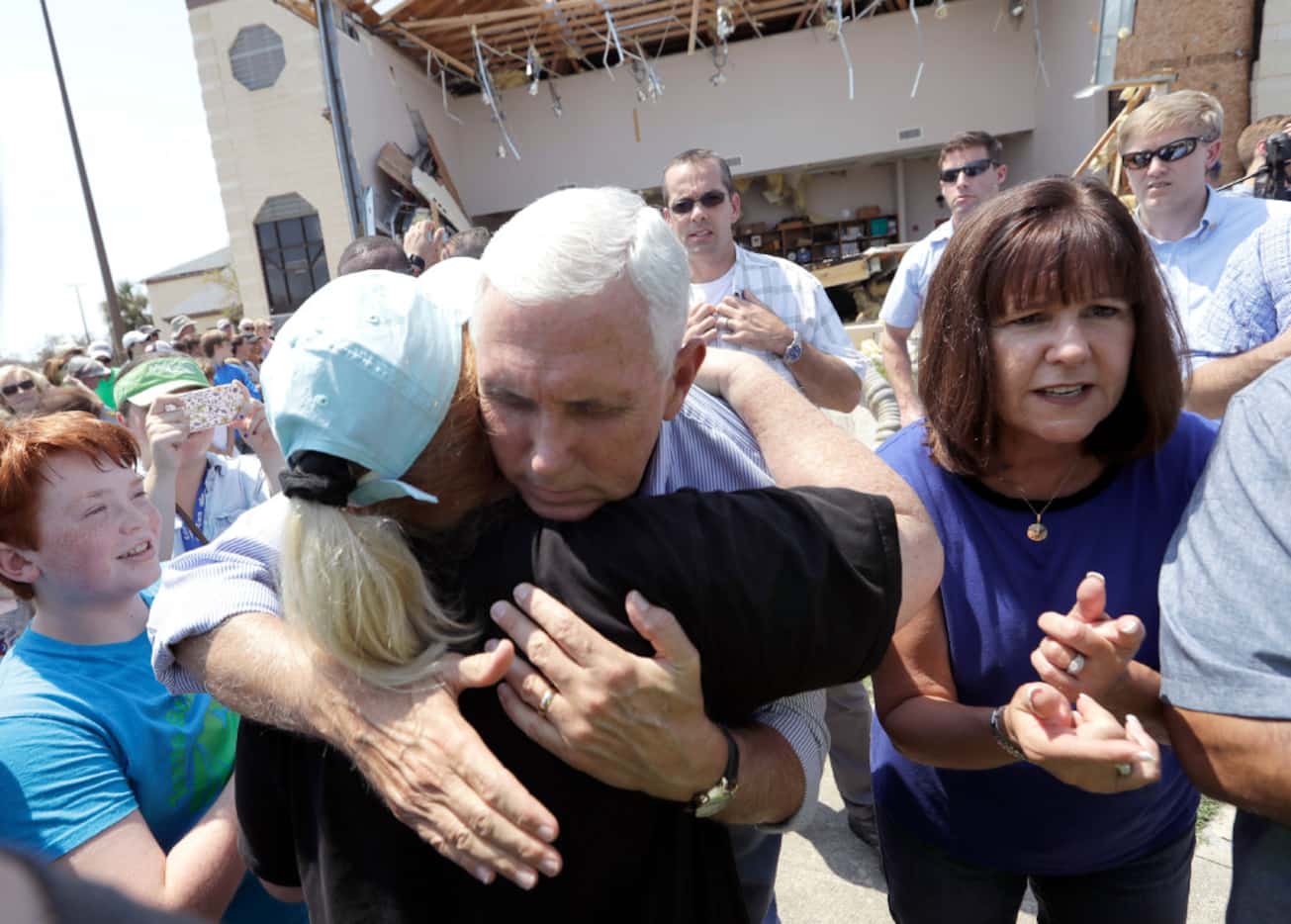 Vice President Mike Pence, with his wife Karen by his side, shares a hug as he tries to...