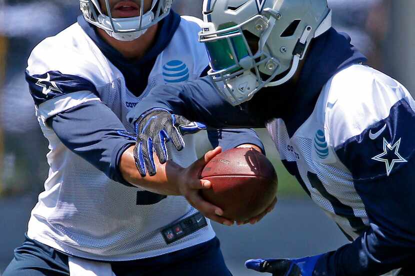 Dallas Cowboys quarterback Dak Prescott, left, hands with ball to running back Ezekiel...