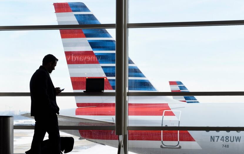 A passenger talks on the phone as American Airlines jets sit parked at their gates at...