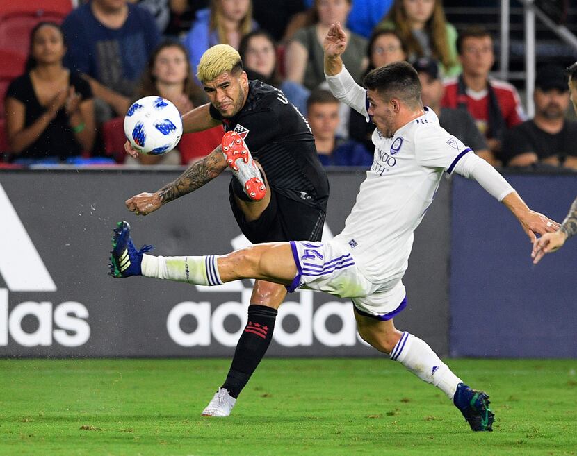 D.C. United midfielder Ulises Segura, left, kicks the ball past Orlando City defender PC...