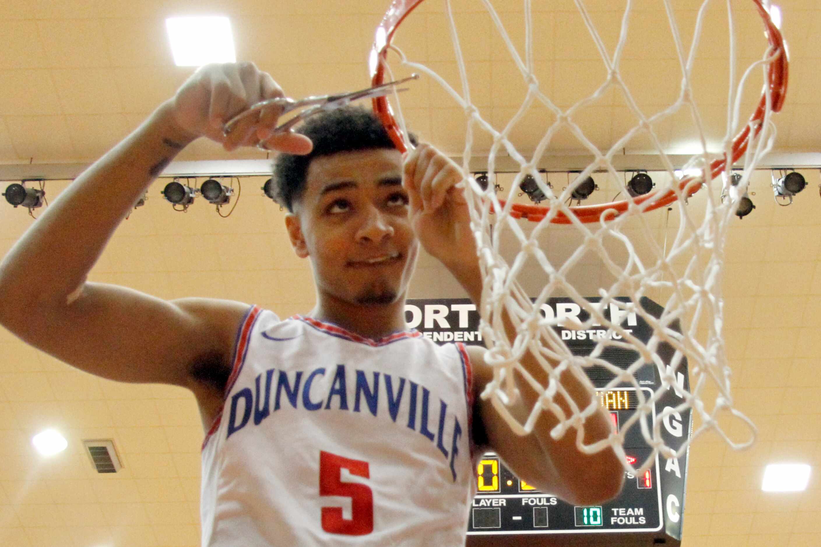 Duncanville senior guard Micah Peavy (5) cuts a portion of the net from the rim following...
