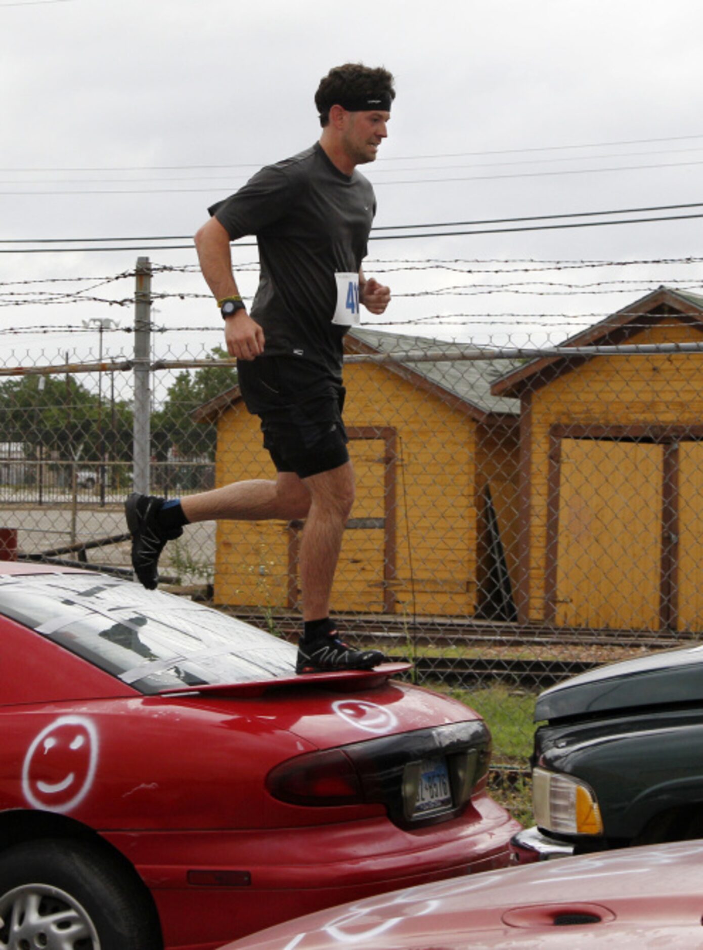 Kyle Larque runs on top of junk car during the Second Annual Fair Park 5K Urban Dash...