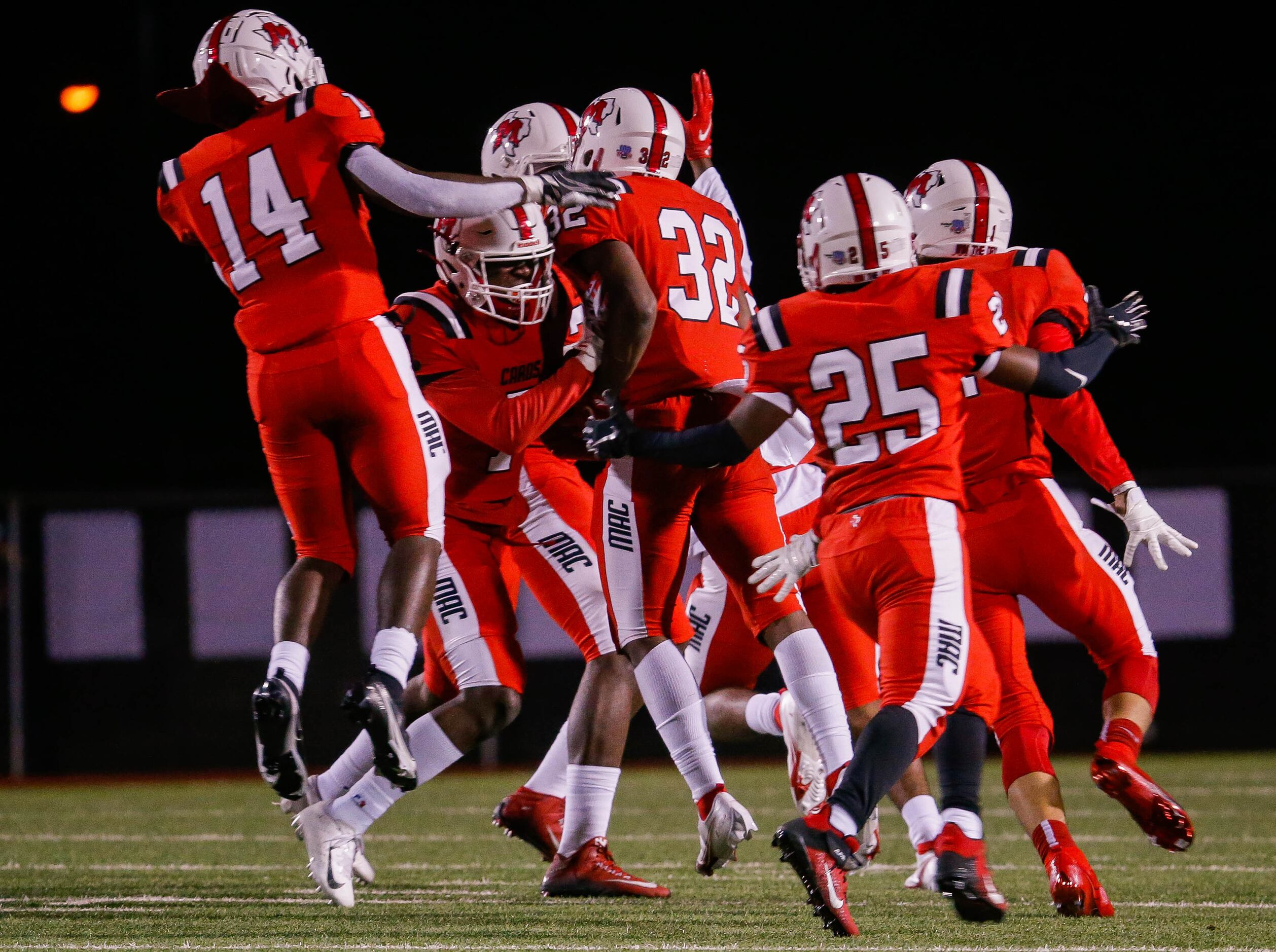 Irving MacArthur players celebrate Aaron Reagan's (32) interception during a the first half...