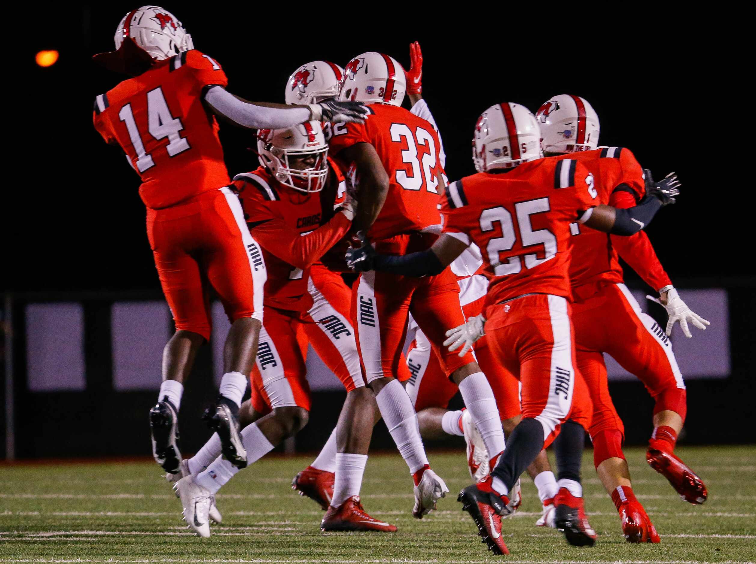 Irving MacArthur players celebrate Aaron Reagan's (32) interception during a the first half...