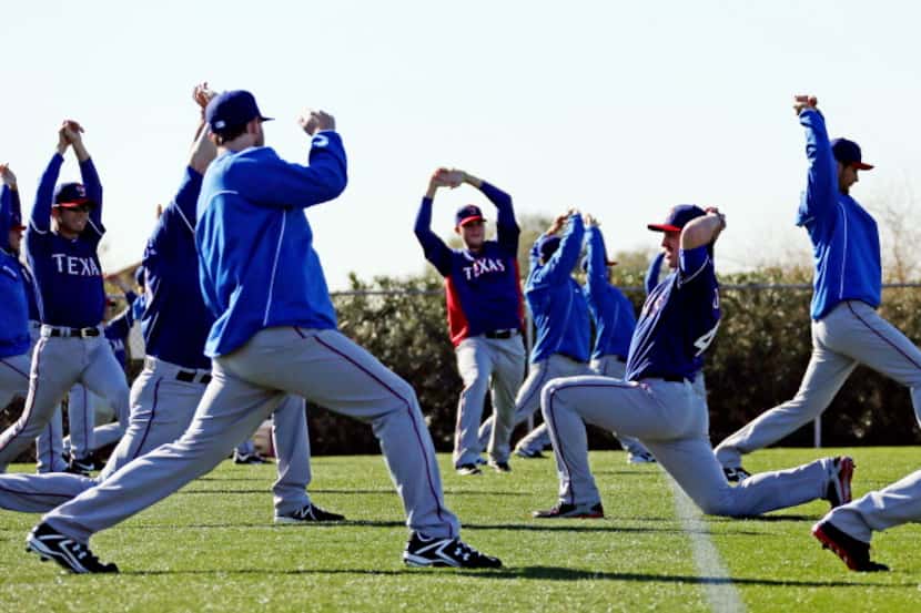 Texas pitcher Derek Holland (center) goes the opposite direction of his teammates during a...