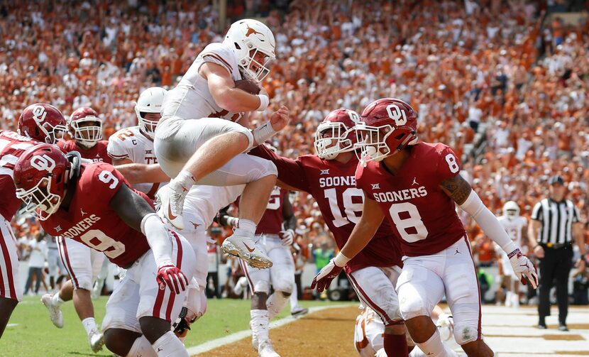 Texas Longhorns quarterback Sam Ehlinger (11) leaps over Oklahoma Sooners linebacker Kenneth...