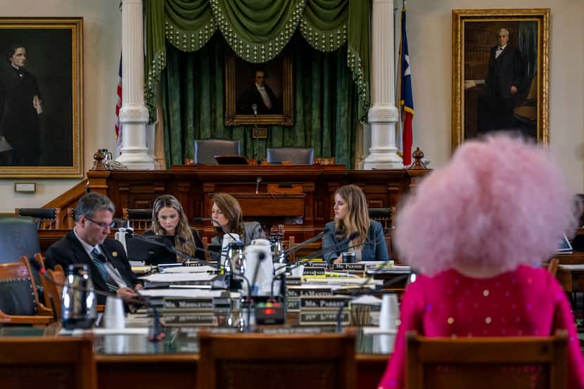 Legislators talk amongst themselves as Texas drag queen Brigitte Bandit prepares to give...