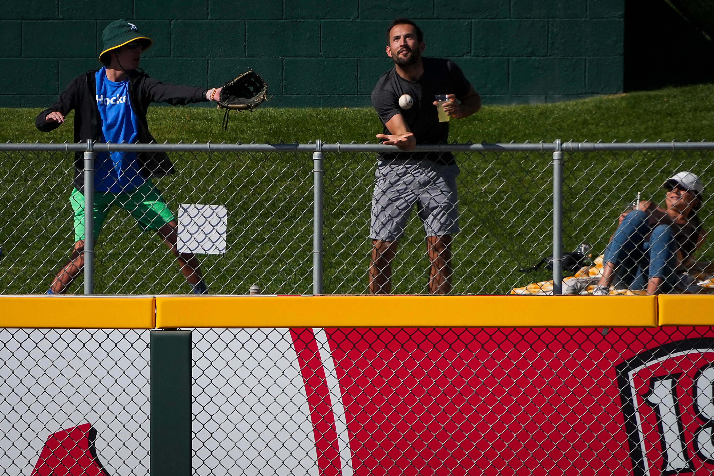 A fan on the outfield berm can’t make a catch on a home run off the bat of Texas Rangers...