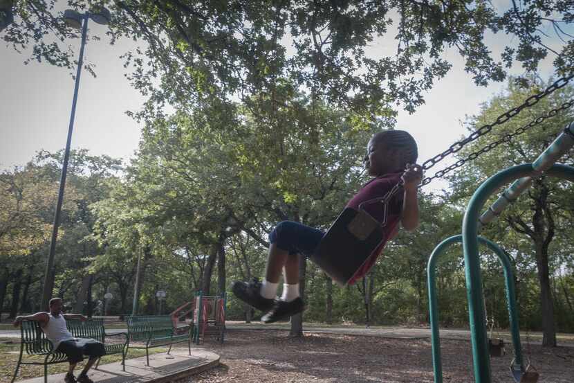 A young girl swings with abandon at a Dallas park.
