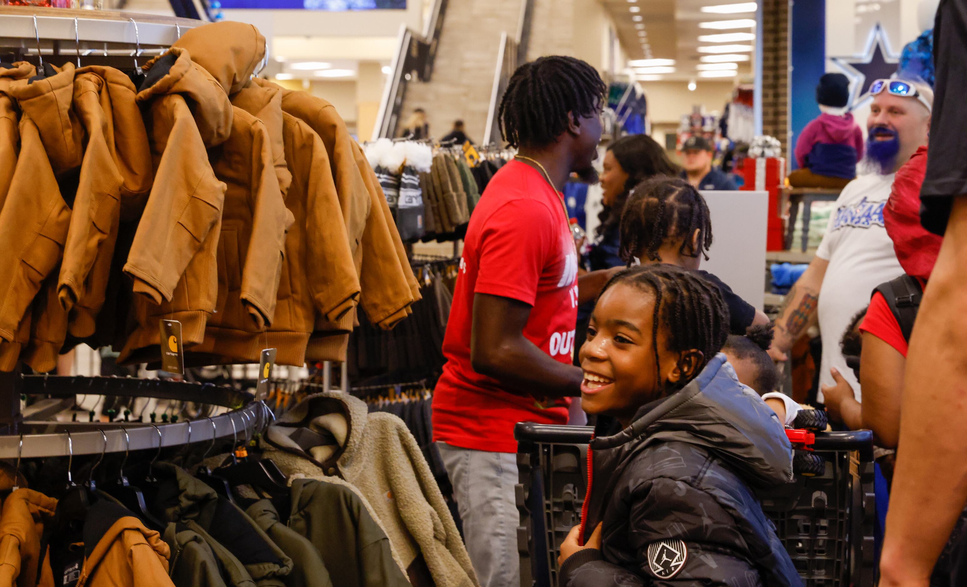 Derrick Givens, Jr., 9, smiles while pulling on a new Jordan jacket while shopping with...