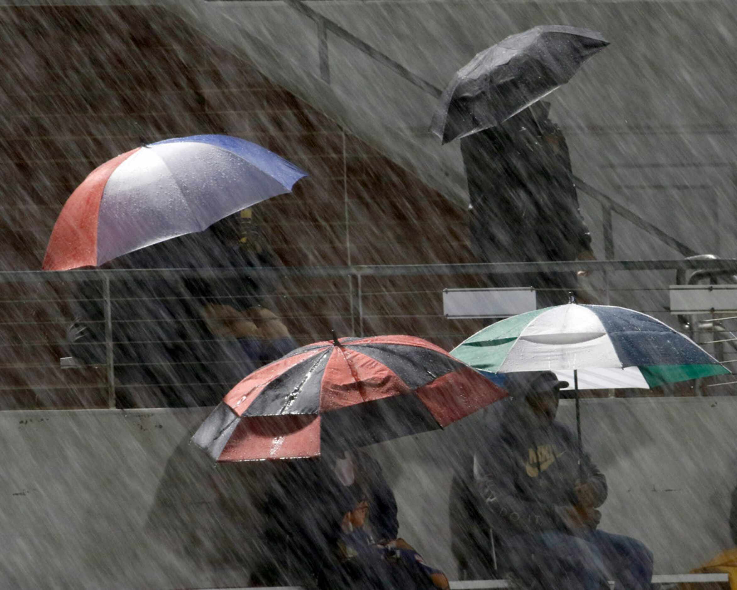 Fans seek shelter under umbrellas during a rained soaked game between Mansfield Summit and...