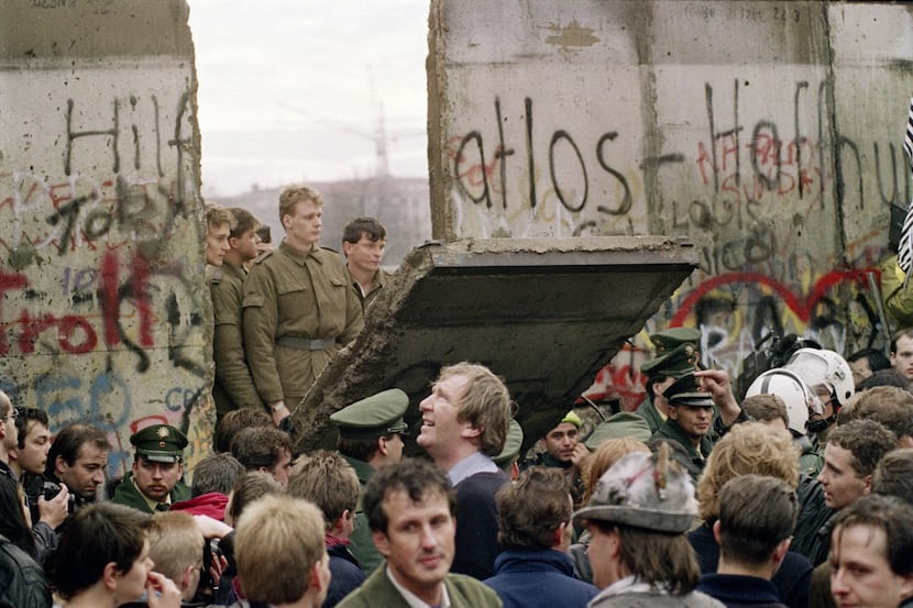 West Berliners crowd in front of the Berlin Wall in 1989 as they watch East German border...