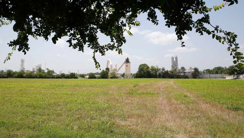 A large field separates the Texas Materials Group asphalt plant from a nearby neighborhood...