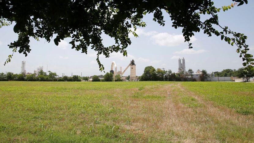 A large field separates the Texas Materials Group asphalt plant from a nearby neighborhood...